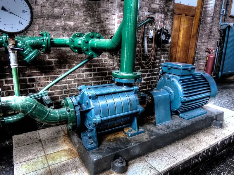 Multistage centrifugal process pump and motor on a plinth beside painted pipework